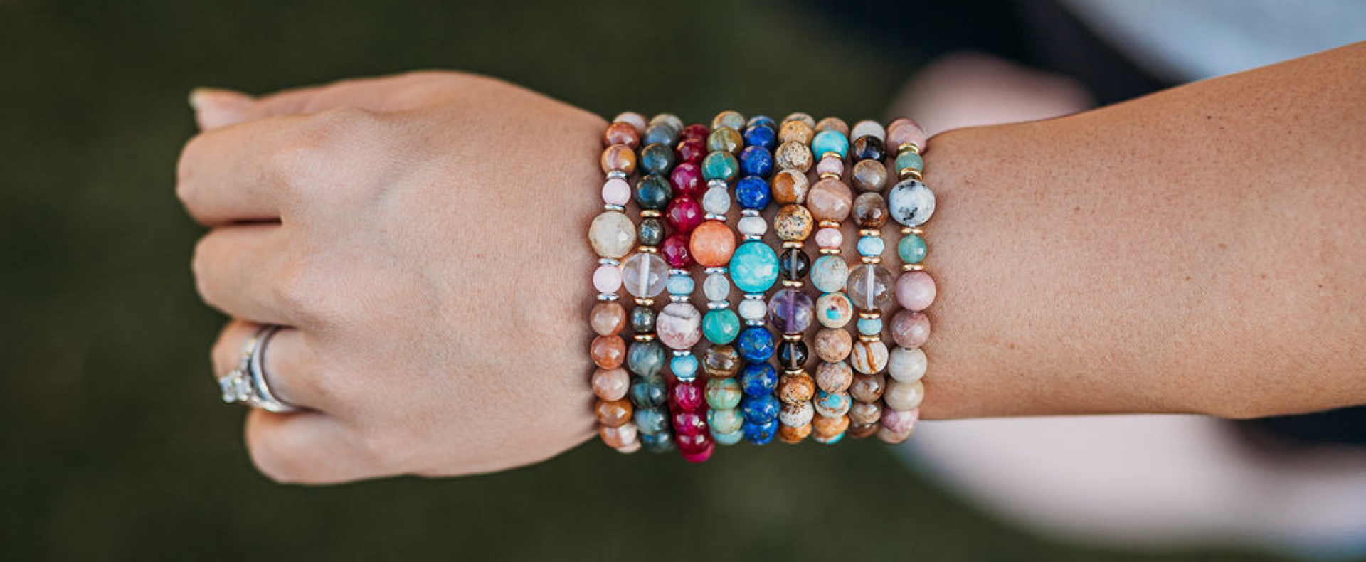 Women's hand and wrist with multiple bracelets on and one ring on.