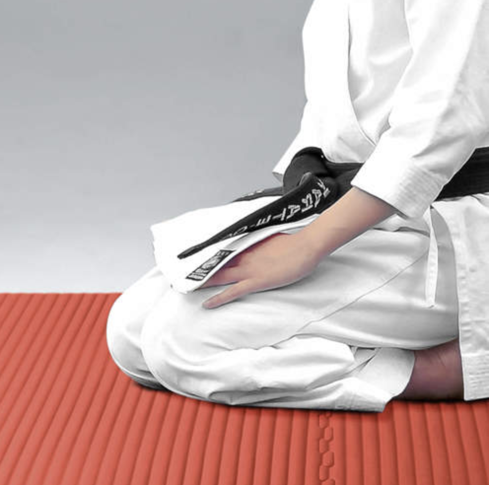 person in martial arts clothing sitting on a mat