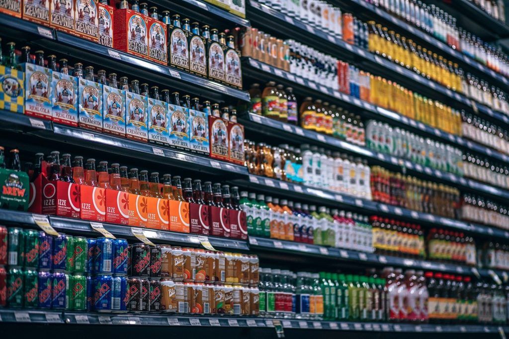 Many bottles and cans of different beverages in a grocery store aisle. 