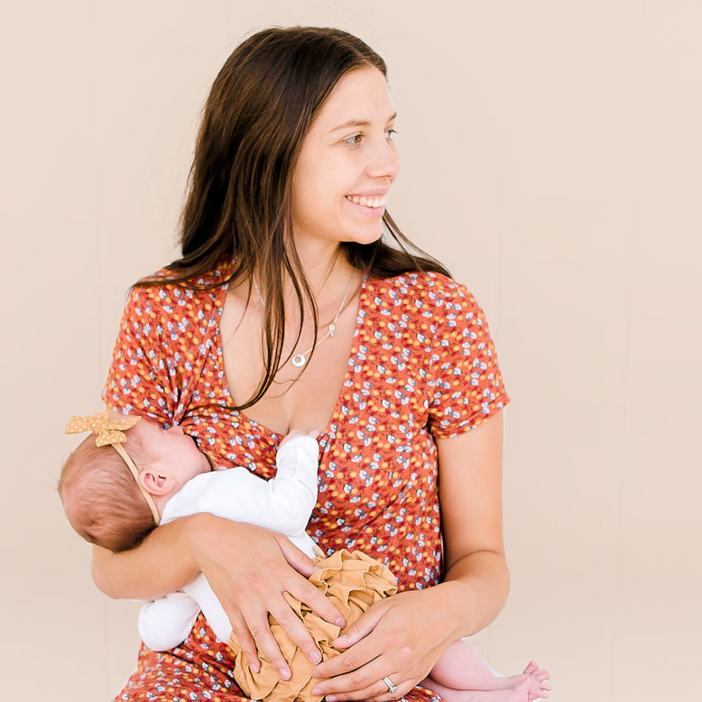 Woman breastfeeding baby wearing orange flowery dress