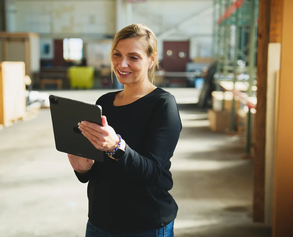 Smiling warehouse worker holding a tablet in a warehouse aisle