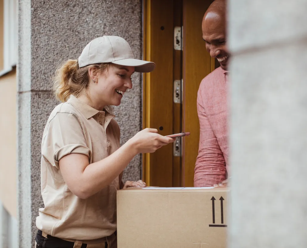 Delivery driver handing a package to a smiling customer at his front door
