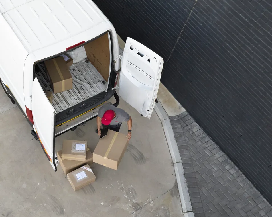 Delivery driver unloading boxes from the back of a van